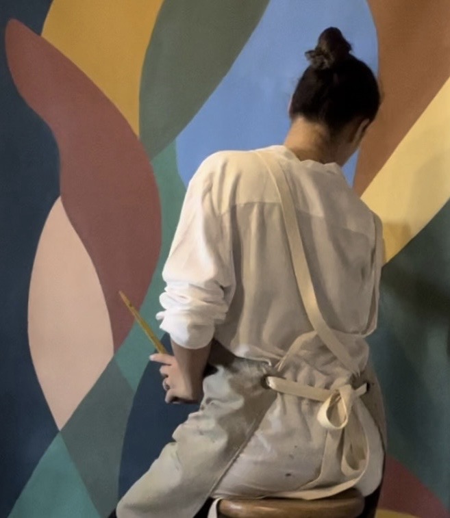 Carina Camargo realizando uma intervenção artística em parede